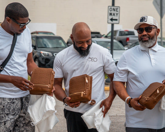 Three men holding brown leather briefcases in a parking lot.